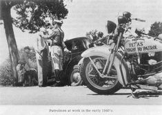 an old black and white photo of men standing next to a parked motorcycle