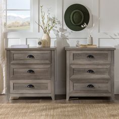 two gray wooden drawers in front of a white wall with a green hat on top