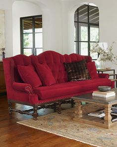 a living room with a red couch and coffee table in front of two large windows