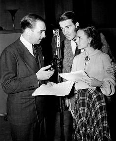 two men and a woman are standing in front of a microphone with papers on it