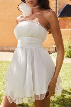 a woman in a short white dress posing for the camera with her hand on her hip