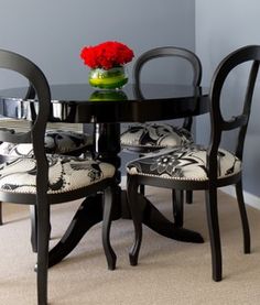 a black table with two chairs and a vase on it