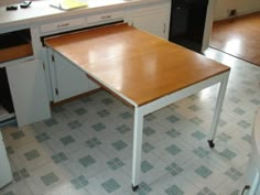 an empty kitchen with white cabinets and wooden table