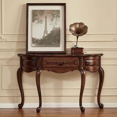 an ornate wooden table with two drawers and a painting on it's sideboard