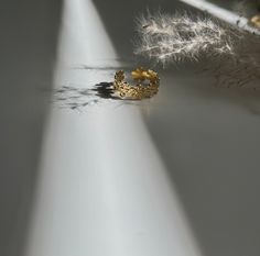 a gold ring sitting on top of a white table next to a feather and some other items