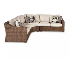 an outdoor sectional couch with pillows on it's back and side facing the camera