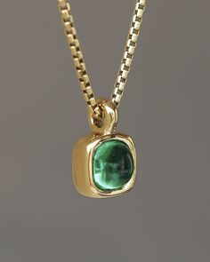 A juicy green emerald rounded square gem inside a solid 18k yellow gold bezel, hanging on a solid 14k yellow gold box chain. Sovereign Pendant by George Rings. Classic Green Emerald Necklace With Bezel Setting, Polished Emerald Jewelry For May Birthstone, Gold Tsavorite Emerald Necklace For May Birthstone, Gold Emerald Jewelry With Cabochon, Formal Green Emerald Necklace In 14k Gold, Yellow Gold Emerald Cabochon Jewelry, Gold Cabochon Jewelry For May Birthstone, Green Emerald Pendant Necklace For Formal Occasions, Gold Tsavorite Emerald Necklace As Gift