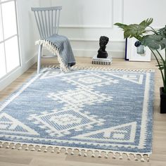 a blue and white area rug with tassels on the floor next to a chair