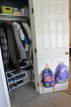 an open closet with shoes and backpacks hanging on the wall next to it's door