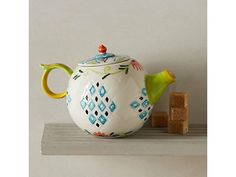 a ceramic teapot sitting on top of a shelf next to a piece of bread