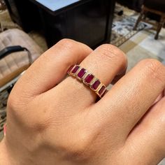 a woman's hand holding a ring with three stones on the middle of it