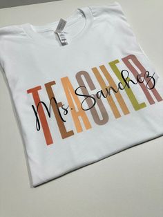 Show your appreciation for your favorite teacher with our Personalized Teacher Shirt! This custom tee makes the perfect gift for new teachers or as a thank you to your mentor. Celebrate their dedication with this unique and thoughtful Teacher Appreciation Gift. How to order 1-pick size and shirt color 2- Add to cart 3- go to cart and in the instructional box enter the custom name Example: Mrs Hernandez 4-Checkout T-shirt .unisex .eco friendly . regular size . soft & comfy Teacher Shirt With Name, Personalised T-shirt, Vinyl Teacher Shirts, Dtf Shirt Ideas, Teacher T Shirt Outfits, Teacher Cricut Shirts, Name Shirt Ideas, Cricut Projects For Teachers, Tshirt Ideas For Teachers