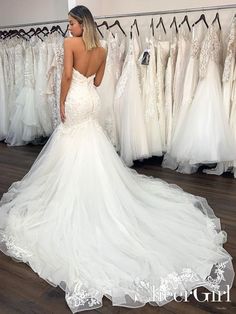 a woman in a wedding dress looking at dresses