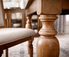 a close up of a wooden table and chair with a rug on the floor next to it