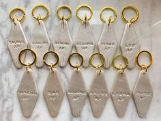 nine pairs of gold and silver key chains with tags attached to them on a marble surface