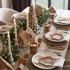 a table set for christmas with gingerbread houses and candles