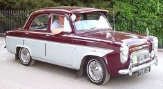 an old red and white car parked in front of a fence