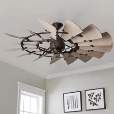 a ceiling fan with wooden blades hanging from it's center point in a living room