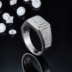 a white gold ring surrounded by diamonds on a black surface with reflections in the background