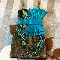 Jianini Haute Couture Jeweled Lace Peacock Mini Dress - Dress Body Is Black Mesh Lace Over Matte Gold Lining - Teal Pleated Waistband With Pleated Horizontal Double Fanned Bow - Sweetheart Neckline With Padded Bra In Lining - Shoulder Straps Are Mesh Covered Gold Lining With Alternating Teal/Gold Jewel Beads - Beneath Waistband Dress Tapers To A Pencil Silhouette - Body Of Dress Is “Feathered” With 1 1/2 Iridescent Blue Faceted Beads That Insinuate Peacock Feathers. - Deep Teal Jewel Shaped Bead Pencil Silhouette, Black Jewel, Haute Couture Dresses, Iridescent Blue, Teal And Gold, Body Dress, Gold Line, Peacock Feathers, Padded Bra