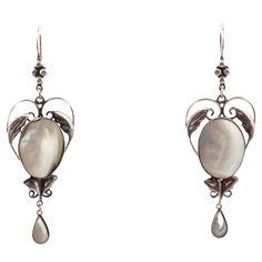 A dramatic size makes these exceptional, hand made, Arts and Crafts earrings atypical. The center is shaped like a heart that delicately frames the oval mother of pearl. Ah the mother of pearl, it has rainbow hues as it moves. Small graceful leaves sit above and below the pearl. The finish is a teardrop of pearl. There is nothing heavy about these earrings. The engraving is fine and delicate in appearance because of the open space design, yet the earrings are strong. Utterly romantic and light on the ear, they are breathtaking for no occasion or for all occasions. The Arts and Crafts movement arose as an answer to the industrial revolution. No machines but rather the jewelry was hand crafted and exhibits natural beauty and natural elements. The workmanship was finely crafted with pride. The Industrial Revolution, Industrial Revolution, Arts And Crafts Movement, Mother Pearl, Natural Elements, The Pearl, Belleza Natural, Space Design, Chandelier Earrings