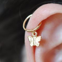 a close up of a person's ear with a butterfly charm attached to it