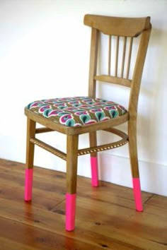 a wooden chair with pink legs and a patterned seat pad