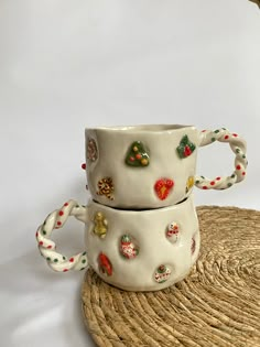 two ceramic mugs sitting on top of a woven place mat next to each other