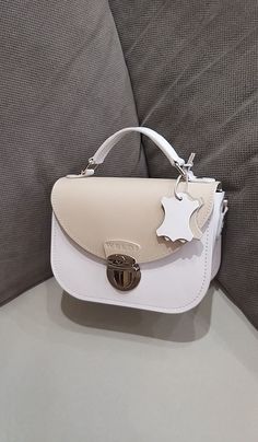 A small white handbag with a light beige lid. Beautiful, charming and very comfortable.  Despite its small size, it is very roomy. Our handbag is made of smooth genuine leather, with a leather lining inside. All edges are processed and painted by hand, making the handbag look neat and expensive. There are two pockets in total inside the bag. The bag closes with a zipper and lock. 🔴You can choose any colors from our palette and make your own unique handbag from them, and we will sew it for you. White Luxury Flap Bag Perfect As A Gift, Luxury White Flap Bag As A Gift, Cream Flap Bag With Detachable Strap For Daily Use, Beige Box Bag With Adjustable Strap As Gift, Cream Bag With Adjustable Strap As Gift, White Flap Bag With Top Handle For Gift, Beige Satchel Shoulder Bag As Gift, White Top Handle Flap Bag For Gift, Cream Top Handle Flap Bag For Everyday