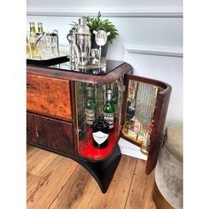 a wooden table topped with lots of bottles and glasses next to a dresser filled with liquor