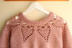 a pink sweater hanging on a wooden hanger