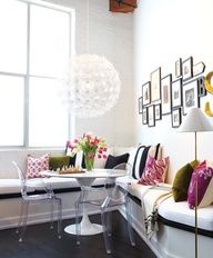 a living room filled with white furniture and lots of pictures on the wall above it