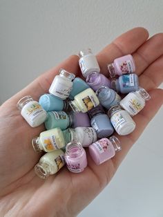 a hand holding a bunch of small baby bottles in it's palm and the top one is filled with them