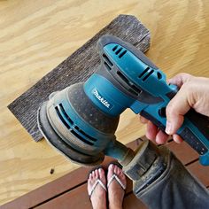 a person is holding a drill in front of a wooden bench with their feet on the ground