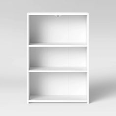 an empty white bookcase with three shelves on one side and the other half open