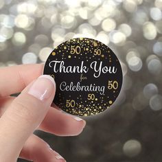 a hand holding a black and gold 50th birthday sticker that says, thank you for celebrating 50 years