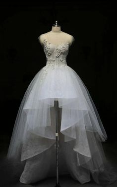 a white wedding dress on display in front of a black background