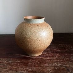 a brown vase sitting on top of a wooden table