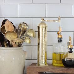 kitchen utensils and cooking utensils are sitting on a counter next to a white tile wall