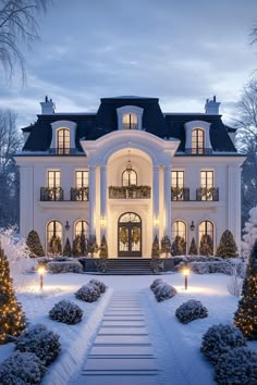 a large white house with lots of windows and lights on it's front porch