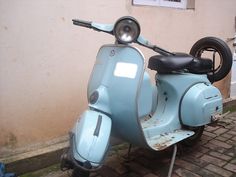 a blue scooter parked next to a building on a cobblestone street