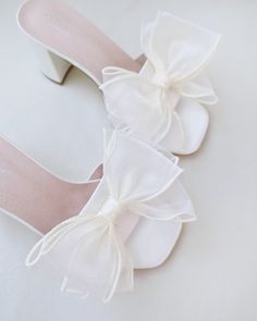 Classic satin slip on block heel sandals accented with oversized layered organza bow for a sweet and romantic look. Simple and easy wear for bridal wear, bridesmaids, holiday party, wedding parties, and any special occasions. DETAILS: HEEL HEIGHT: 2.5 InchesCOLORS AVAILABLE: White & IvoryUPPER: Synthetic upper and liningMATERIALS: Manmade outsole Summer Block Heels With Satin Bow, Summer White Heels With Satin Bow, White Sandals With Satin Bow And Ankle Strap, Feminine Wedding Heels With Satin Bow, White Wedding Shoes With Satin Bow And Block Heel, Block Heels Wedding, Bridal Sandals, White Heels, Satin Slip