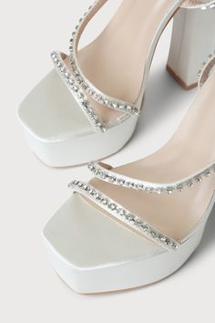 Lulus Exclusive! Feel like you're stepping out onto the stage in the Lulus Sinia Ivory Satin Rhinestone Platform High Heel Sandals! Sleek satin shapes these statement-making heels that have a square toe footbed atop a 1.75"" toe platform. Clear rhinestones, in silver settings, adorn the toe strap, vamp strap, and the matching wrapping ankle strap that secures with a silver buckle. 5. 5" wrapped black heel. Cushioned insole. Felted rubber sole has nonskid markings. Man made materials. Imported. L Satin Heels With Rhinestones For Prom, Glamorous Synthetic Sandals For Wedding, White Satin Evening Sandals, Glamorous Embellished Satin Heels, Glamorous Satin Heels For Prom, Embellished Synthetic Sandals For Wedding, Rhinestone Synthetic Heels For Wedding, Wedding Heels With Rhinestones In Synthetic Material, Satin High Heels