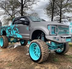 a monster truck with blue wheels parked in the dirt