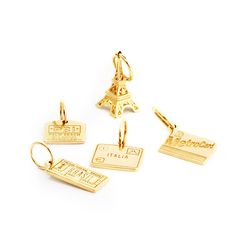 four different types of gold charms on a white background with the word paris written below them