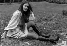 a woman sitting on the ground with her legs crossed and wearing knee high black boots