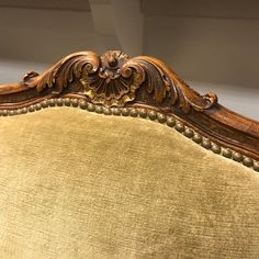 an ornately carved wooden headboard and foot board on a gold upholstered chair