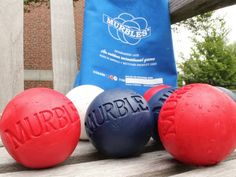 three red, white and blue balls sitting on top of a wooden bench next to a bag