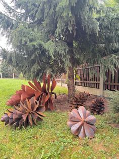 two large metal flowers sitting in the grass next to a tree