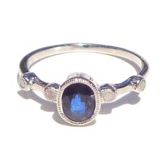 This Darling ring has a Natural, faceted, oval cut, 1.00ctw Genuine Blue Sapphire, (mined, not lab created, with four tiny, 1.5mm, faceted, Genuine Diamonds on the band. The Sapphire is SI color, and 7.40mm North to South. The hight above the finger is 4.85mm, shank width is 1.30mm, and gram weight is 1.8g. The .07ctw Diamonds are round, with I color, and SI Clarity. The ring is .925 Sterling Silver, in a size 7, resizable by your local silver smith or jeweler, if need be. This little Beauty wou Oval Sapphire Ring With Rose Cut Diamonds For Promise, Oval Sapphire Promise Ring With Ethical Diamonds, Oval Birthstone Ring With Rose Cut Diamonds For Promise, Promise Oval Birthstone Ring With Rose Cut Diamonds, Sterling Silver Sapphire Rings With Rose Cut Diamonds, Sapphire Rings With Rose Cut Diamonds In Sterling Silver, Oval Sapphire Diamond Ring With Rose Cut Diamonds, Oval Sapphire Ring With Bezel Setting, Oval Sapphire Ring With Rose Cut Diamonds